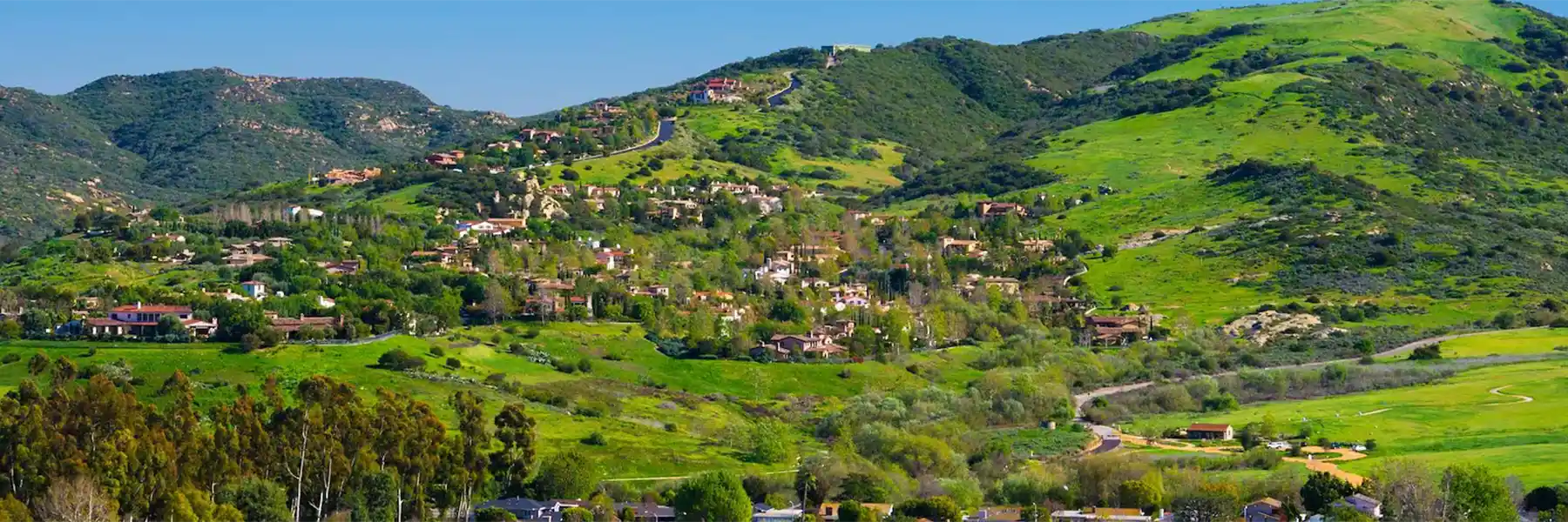 Lush green hills with scenic homes and roads.