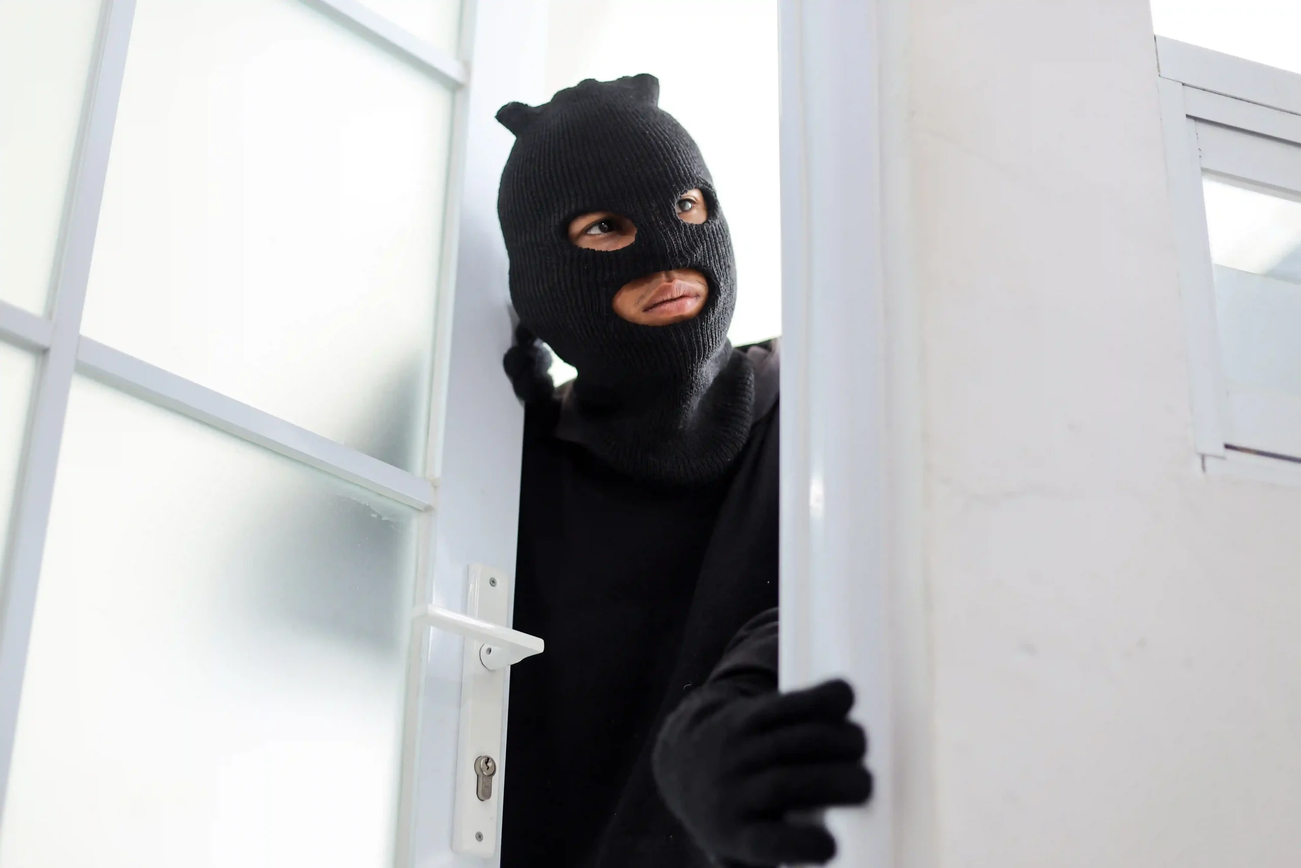 Person in mask peering through a door.