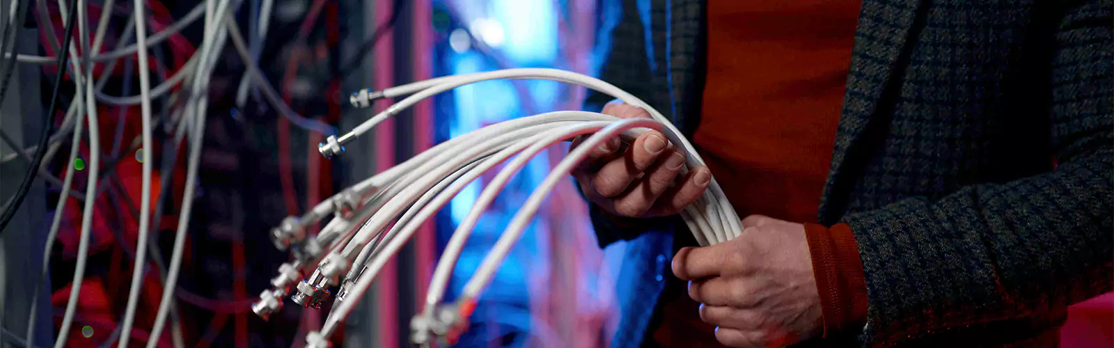 Person holding multiple network cables in server room.