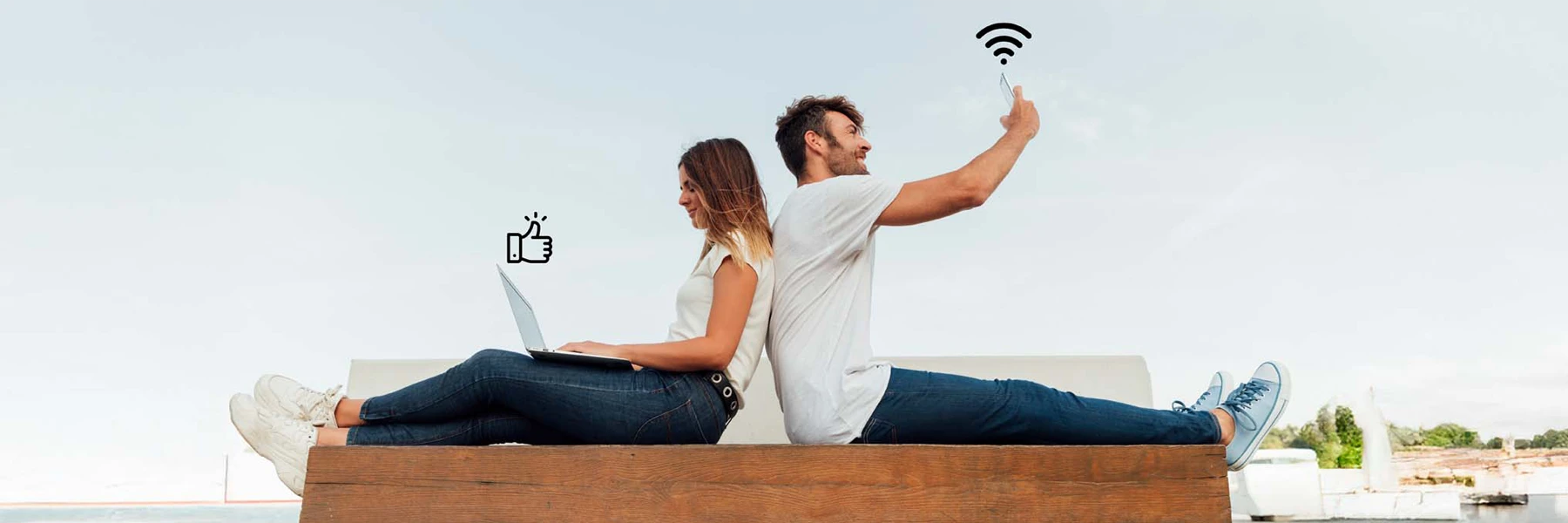 Couple using laptop and smartphone outdoors