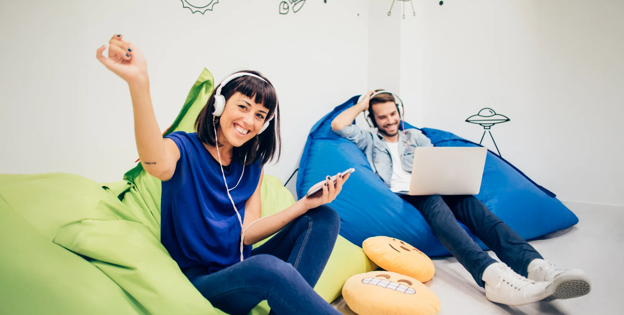 Two people relaxing on bean bags with headphones.