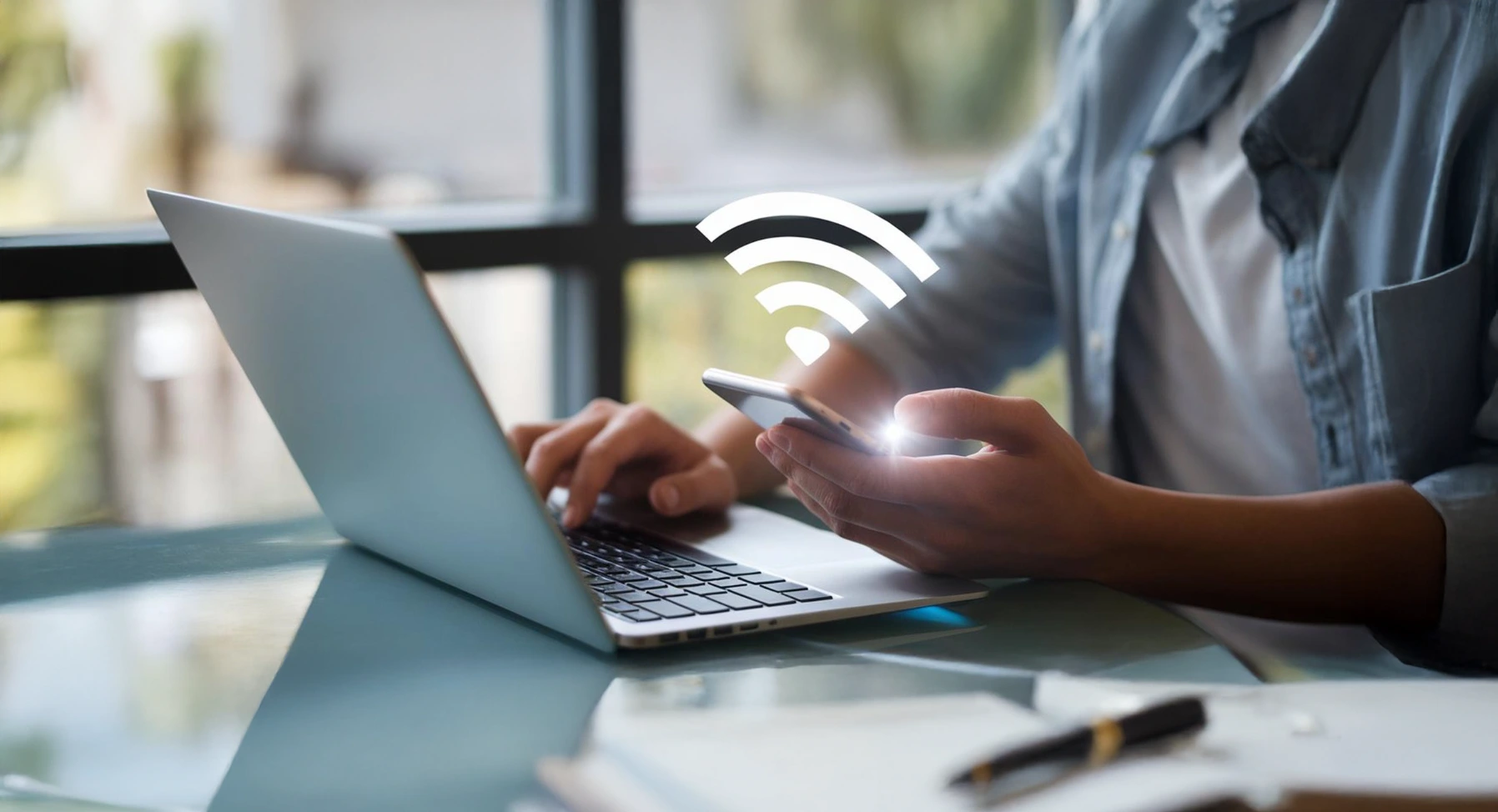 Person using smartphone and laptop with wifi symbol