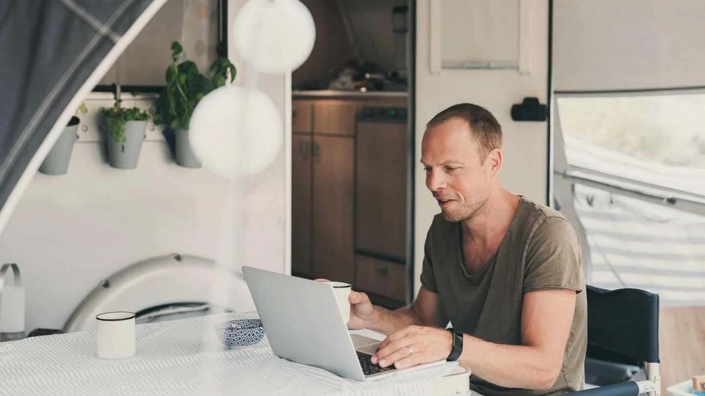 Man working on laptop in a camper