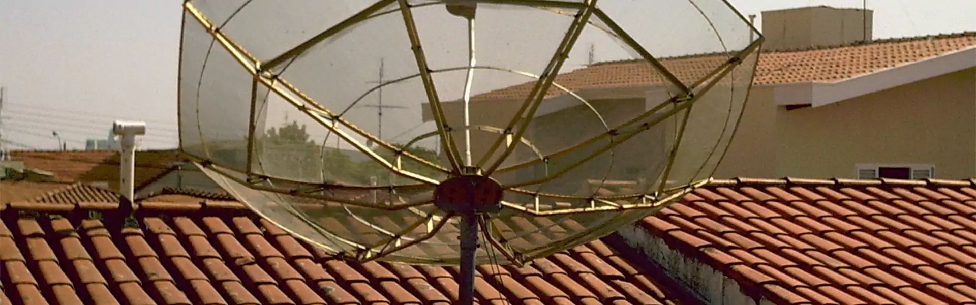 Satellite dish on rooftops against clear sky.