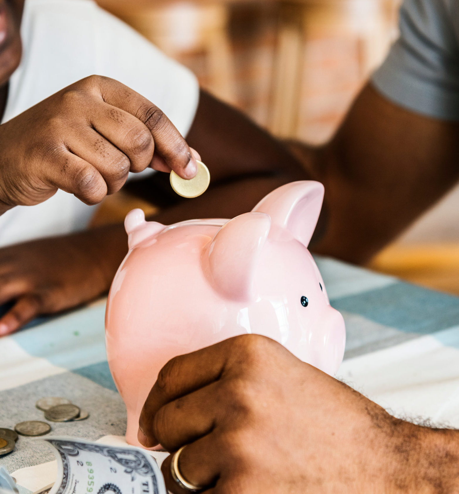 Child deposits coin into a piggy bank.