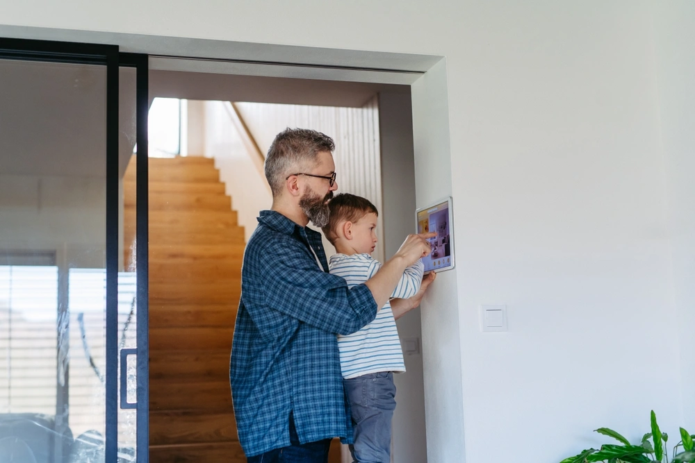 Father helping child with a tablet indoors.