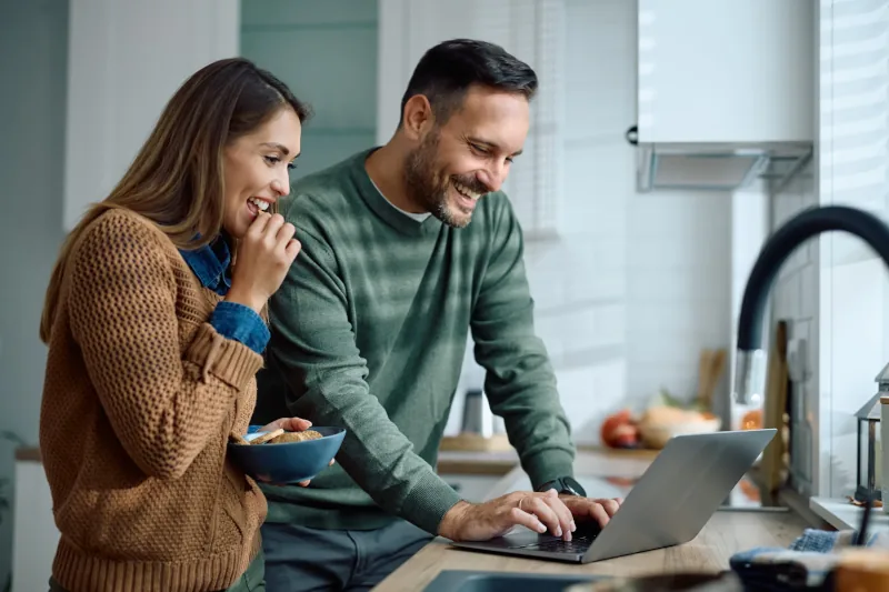Couple enjoying breakfast while using laptop