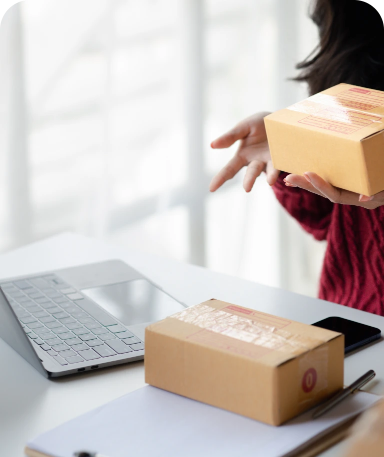 Individual handling packages near a laptop.