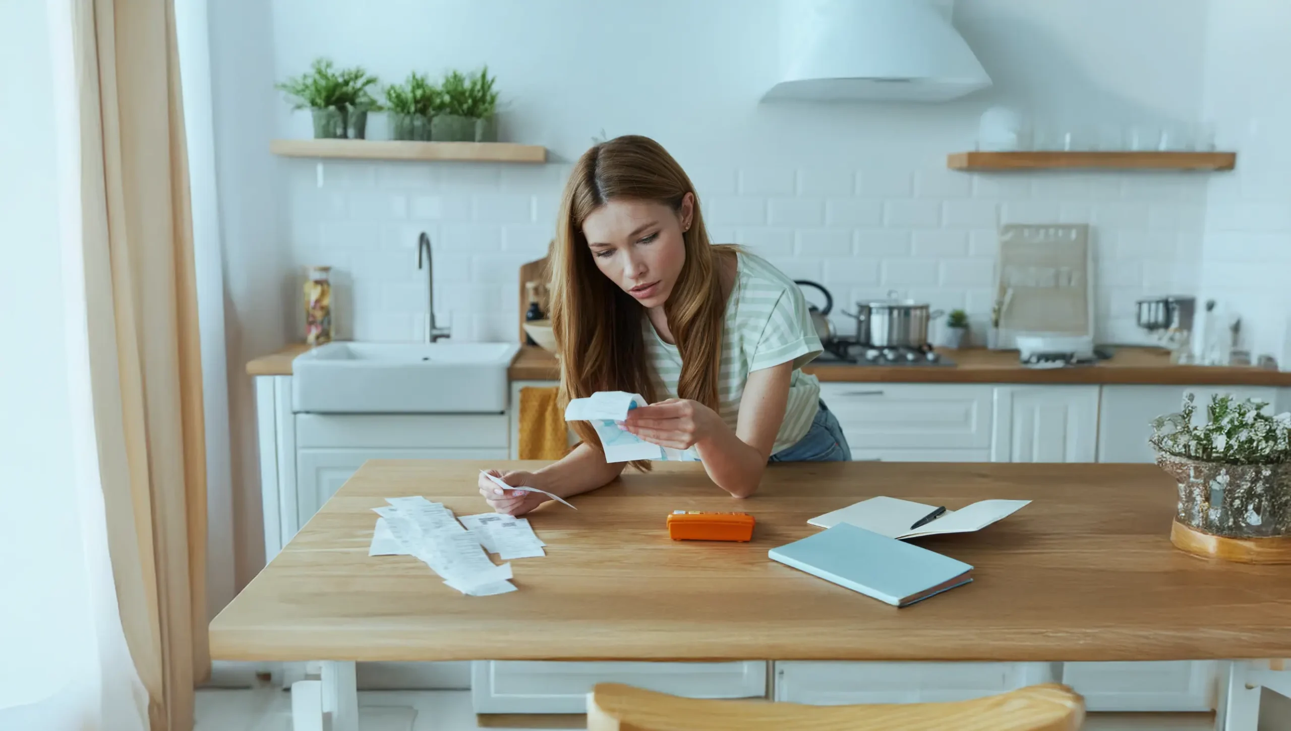 Woman organizing receipts on a kitchen table.