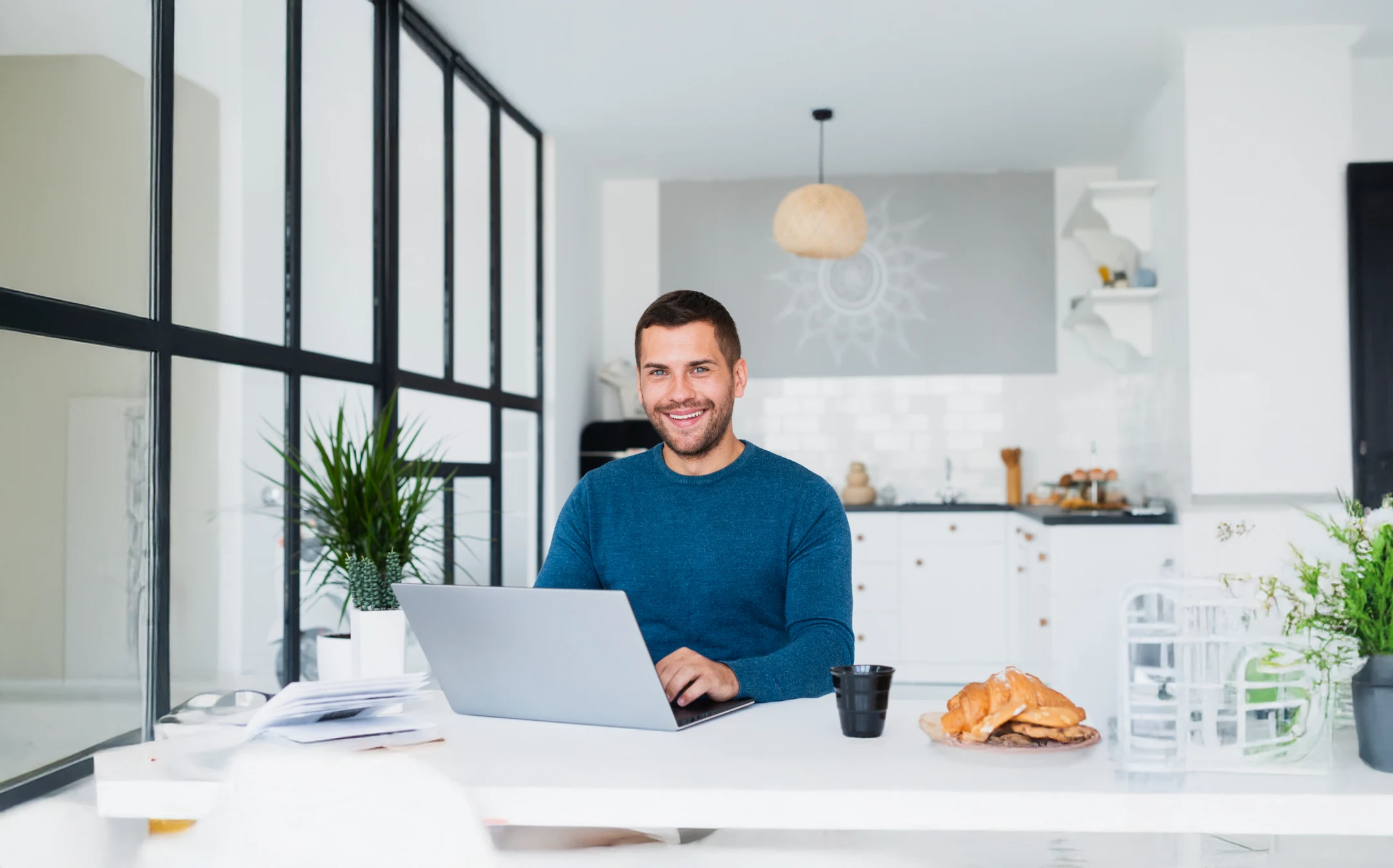 Smiling man working on laptop in modern kitchen