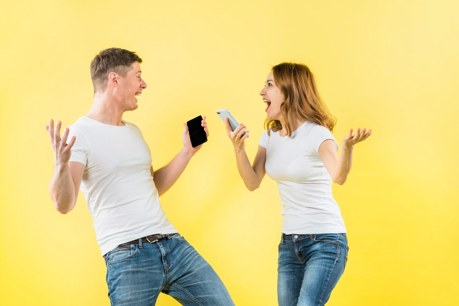 Two people joyfully interacting with smartphones against yellow background.