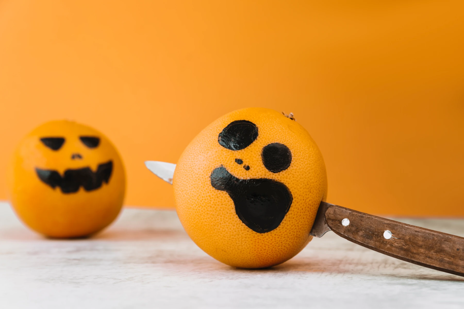 Halloween-themed painted oranges with knife