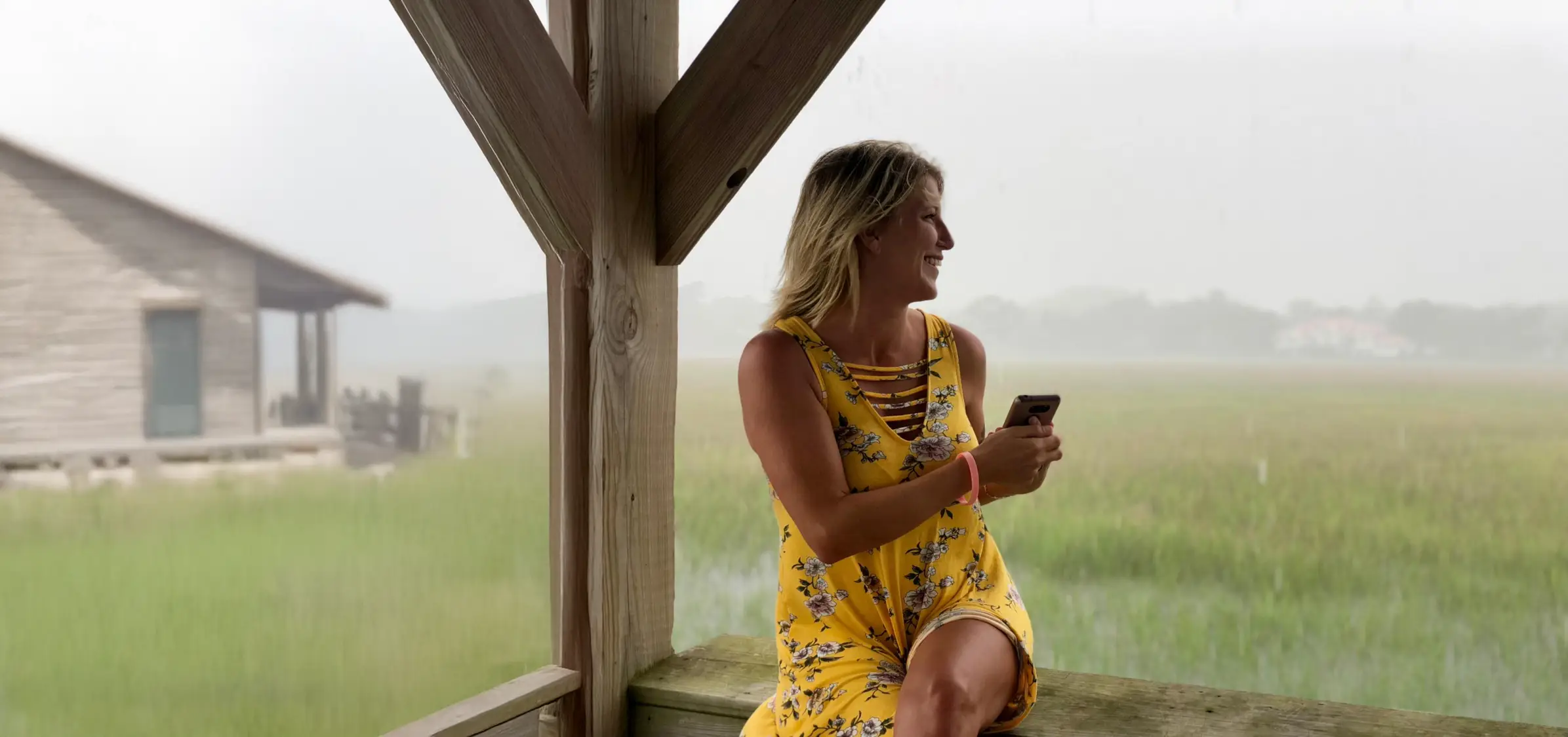 Woman in yellow dress sitting outdoors, looking away.