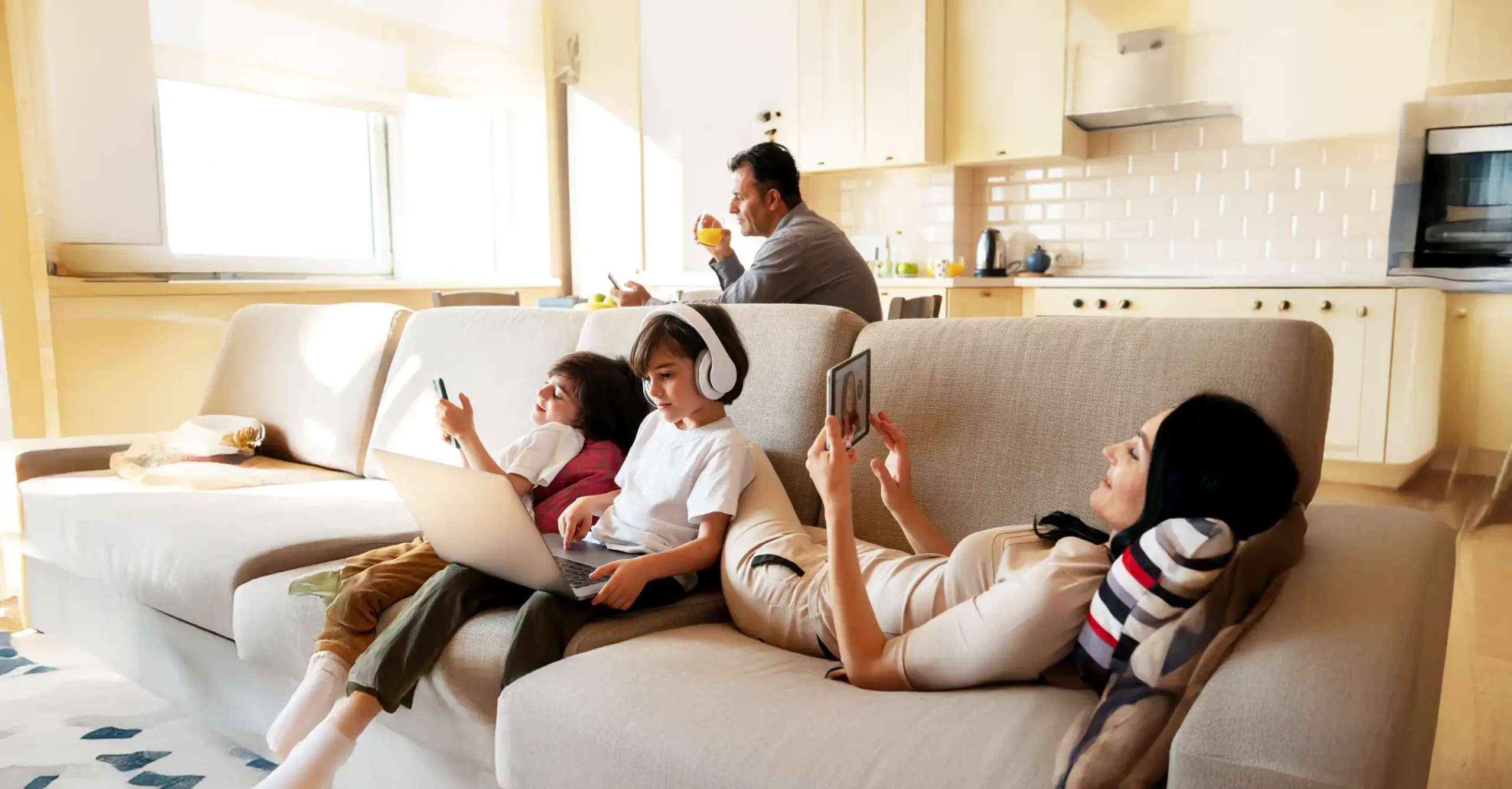 Family relaxing together on a couch with devices.