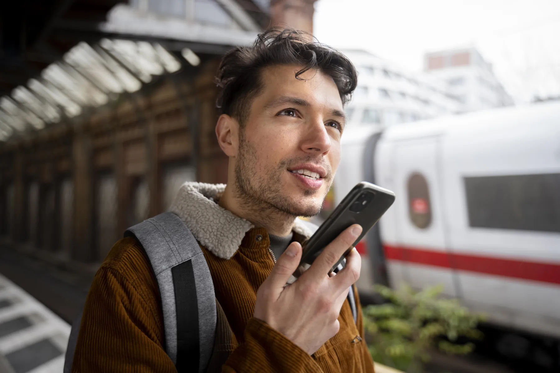 Man using a smartphone at a train station.