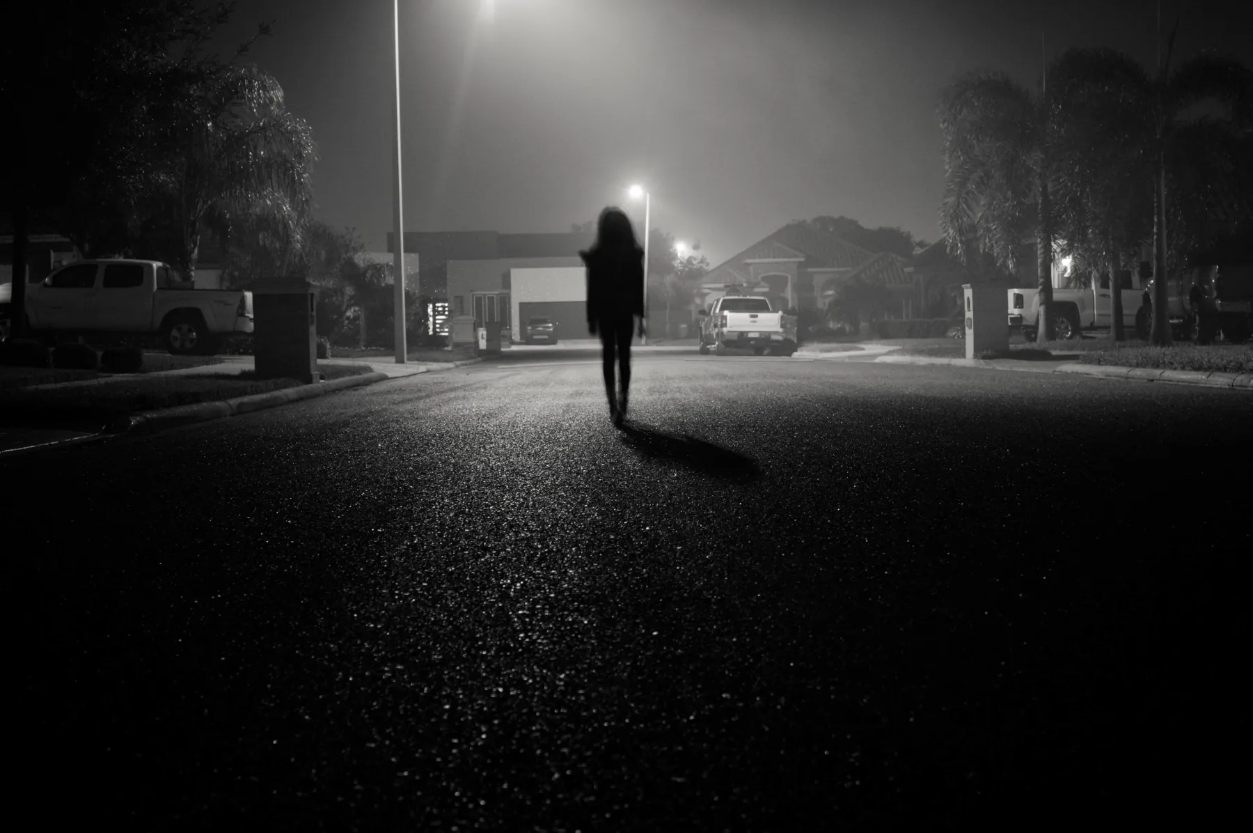 Silhouette walking on a dimly lit street.