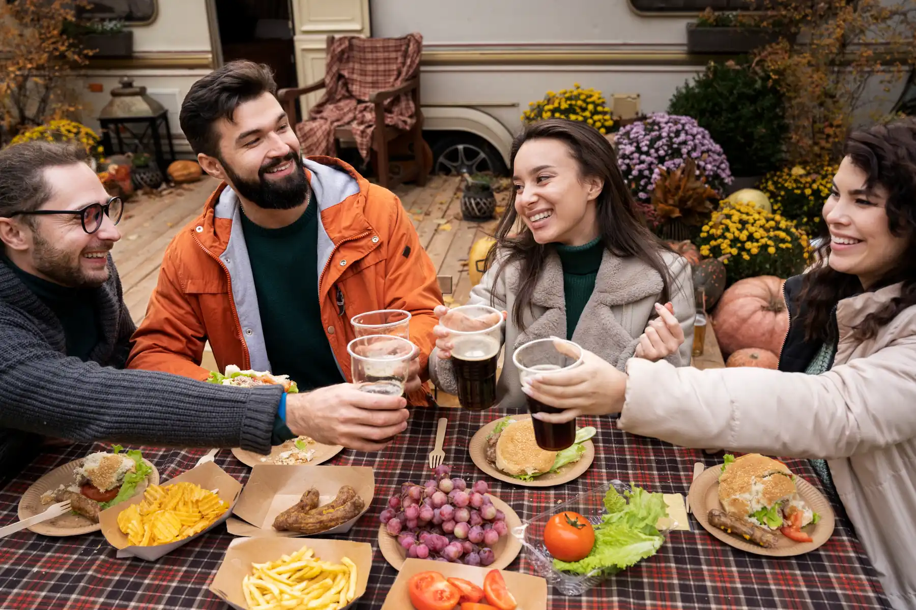Friends enjoying food and drinks outdoors together.