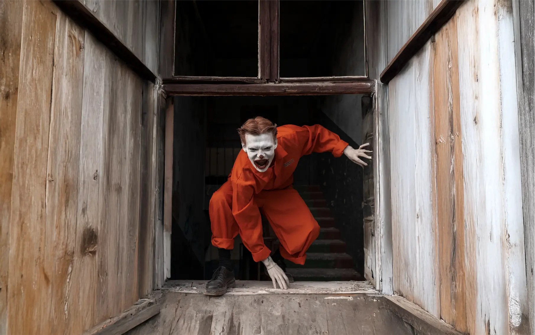 Creepy figure in orange jumpsuit climbing through window.