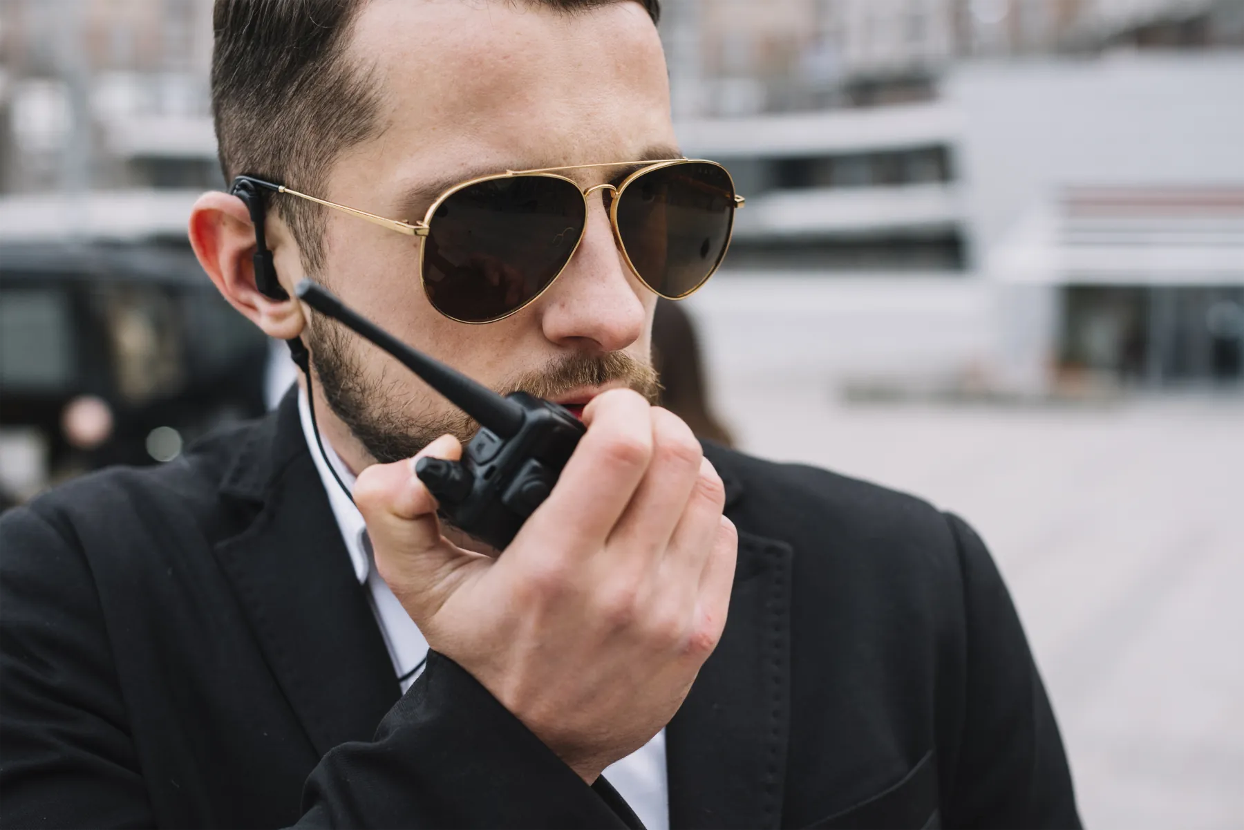 Man in sunglasses using a walkie-talkie.