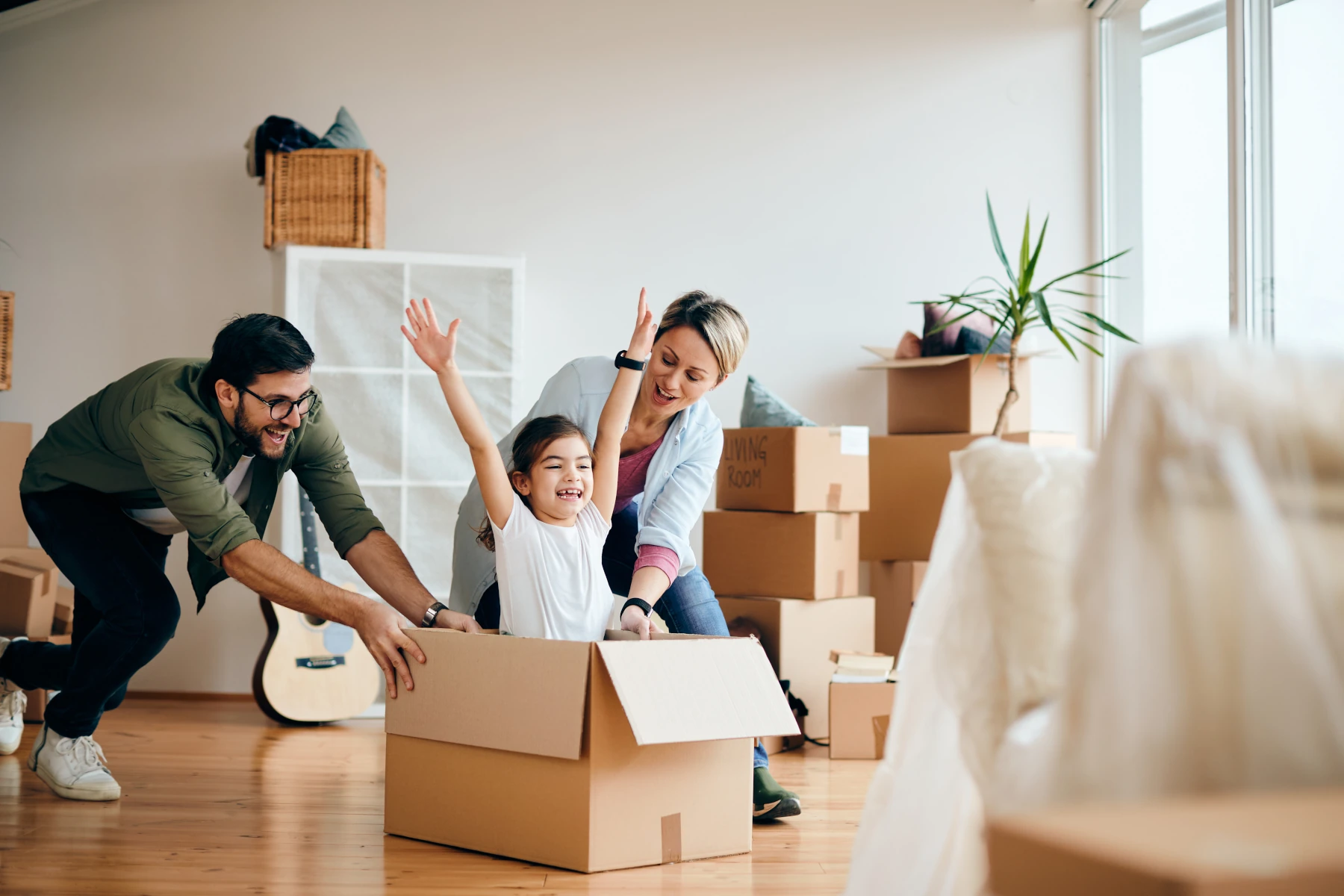 Family playing with moving boxes indoors.